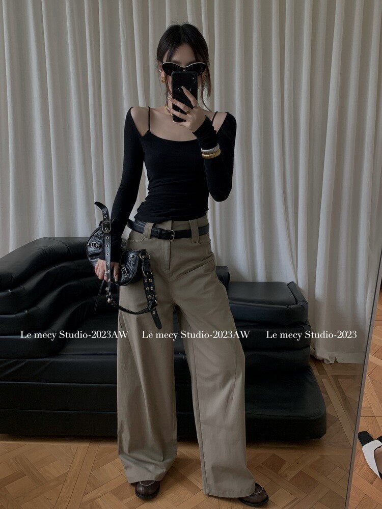 Woman wearing a black long-sleeve top and wide-leg trousers with a small black handbag