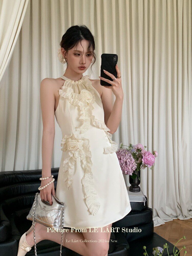 Cream halter mini dress with ruffled floral detailing worn by a model