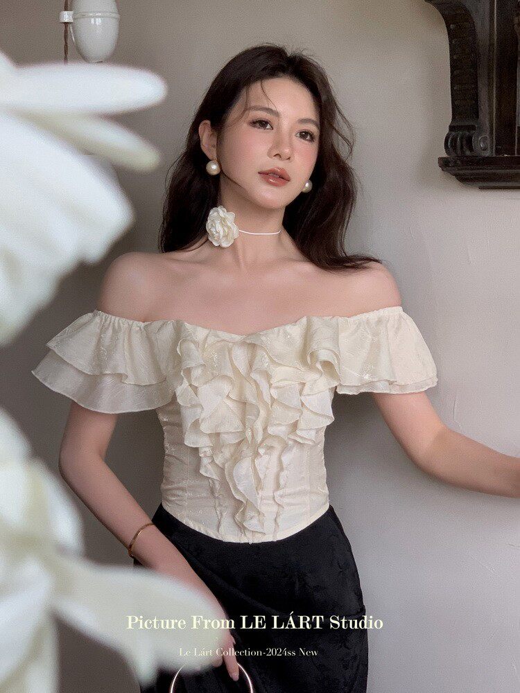 Woman wearing a cream off-shoulder ruffled top with black skirt