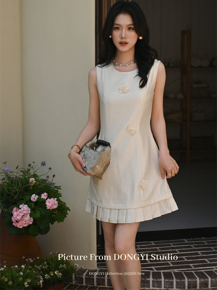 Cream sleeveless mini dress worn by a model with pleated hem