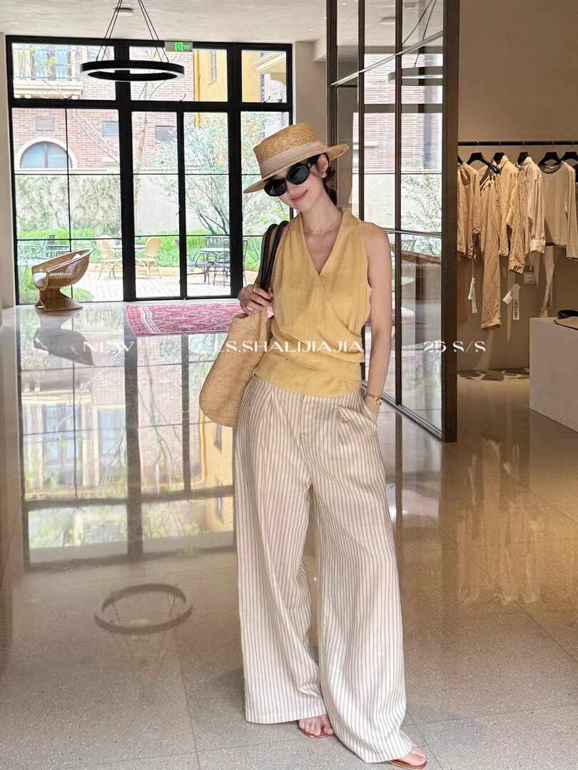 Model wearing a yellow sleeveless top and striped wide-leg pants in a boutique setting