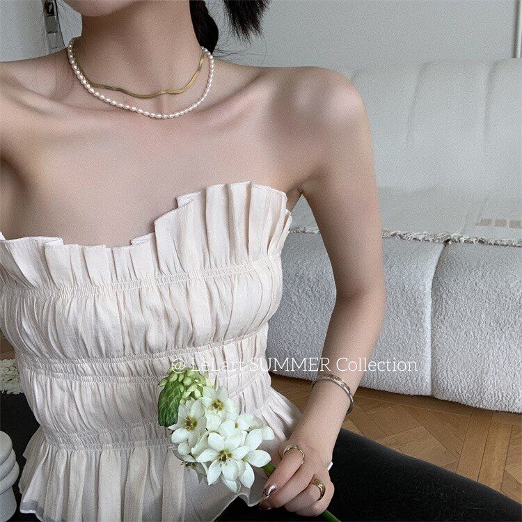 Woman wearing a beige strapless ruched dress with a floral accessory