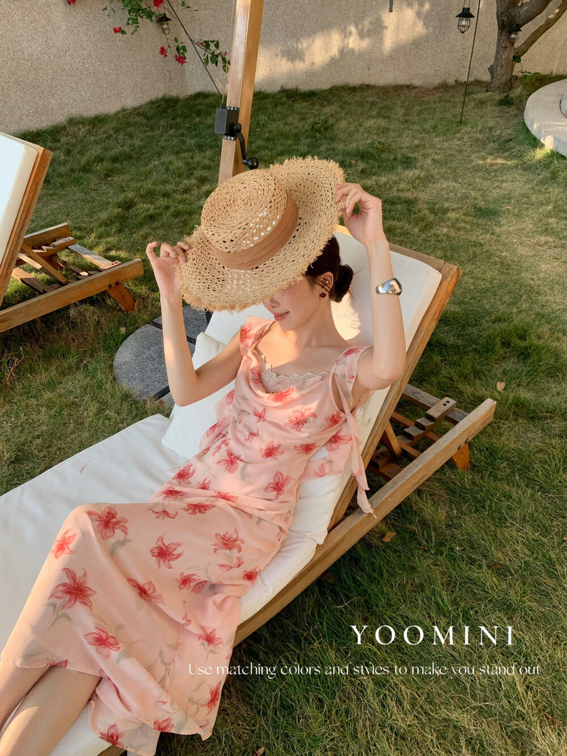 Woman wearing a pink floral summer dress and straw sunhat outdoors