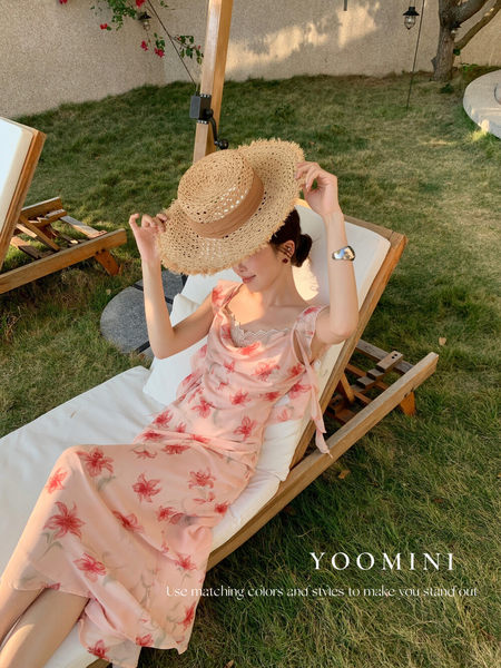 Woman wearing a pink floral summer dress and straw sunhat outdoors