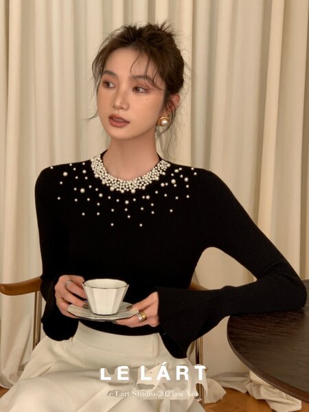 Black pearl-embellished long sleeve top worn by a model