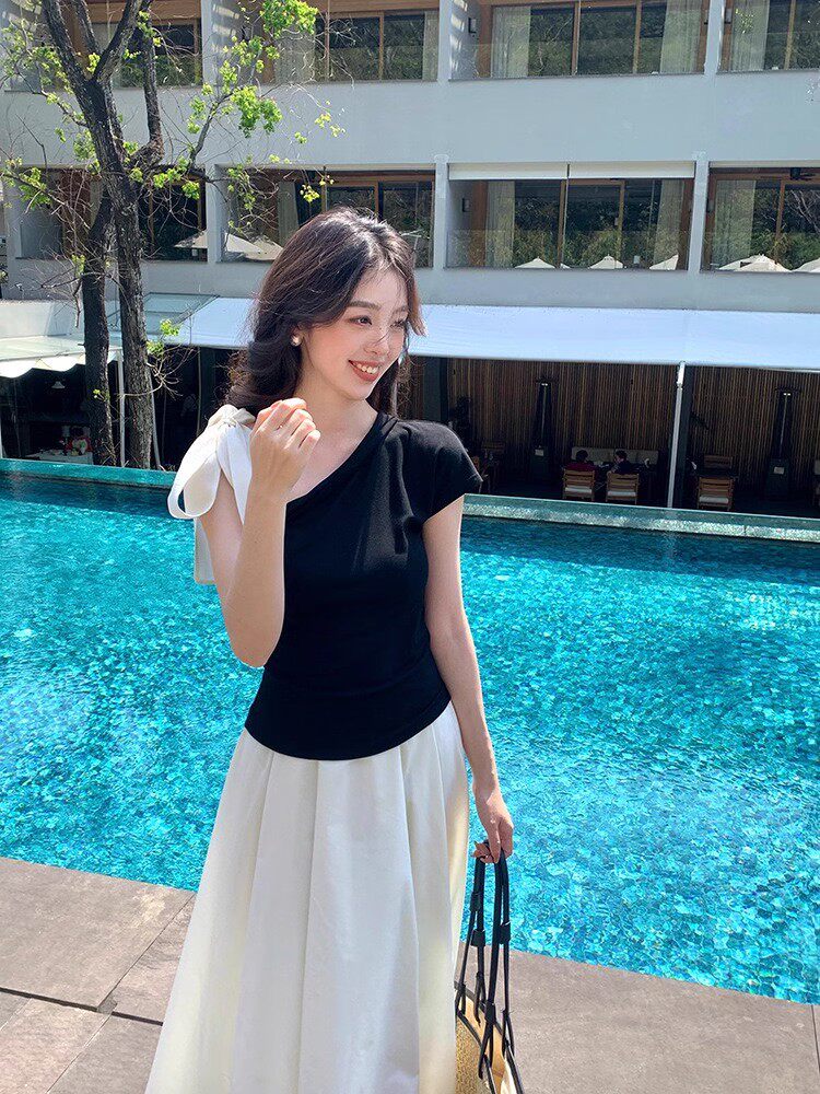 Woman wearing a black top and white skirt by a pool