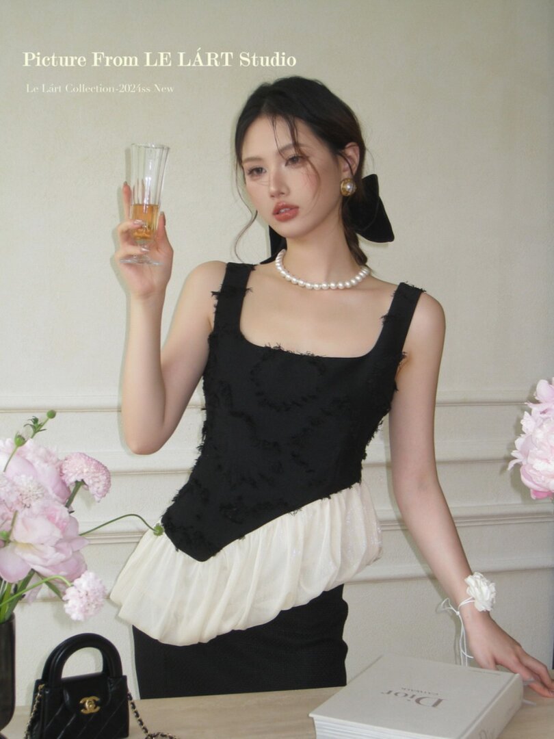 Model wearing a black and white sleeveless dress with a pearl necklace