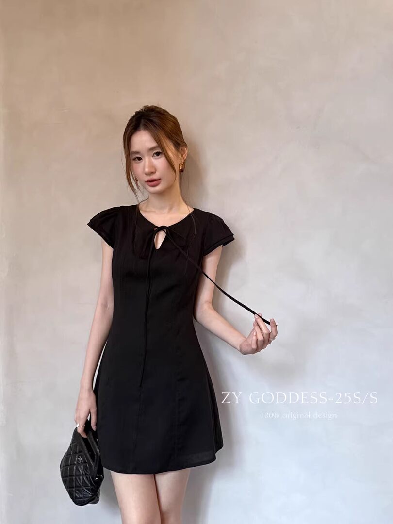 Black short dress worn by a model with a ribbon tie neckline