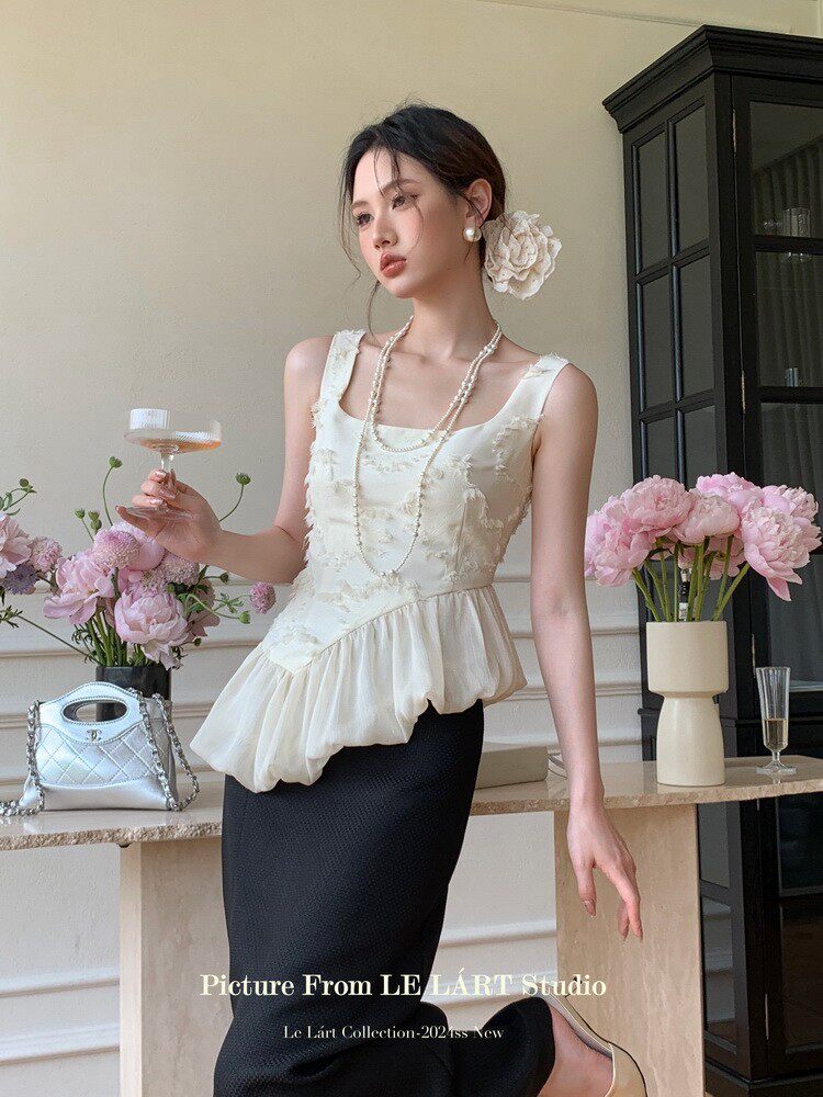 Model wearing a white sleeveless peplum top with a black skirt in a styled fashion photo
