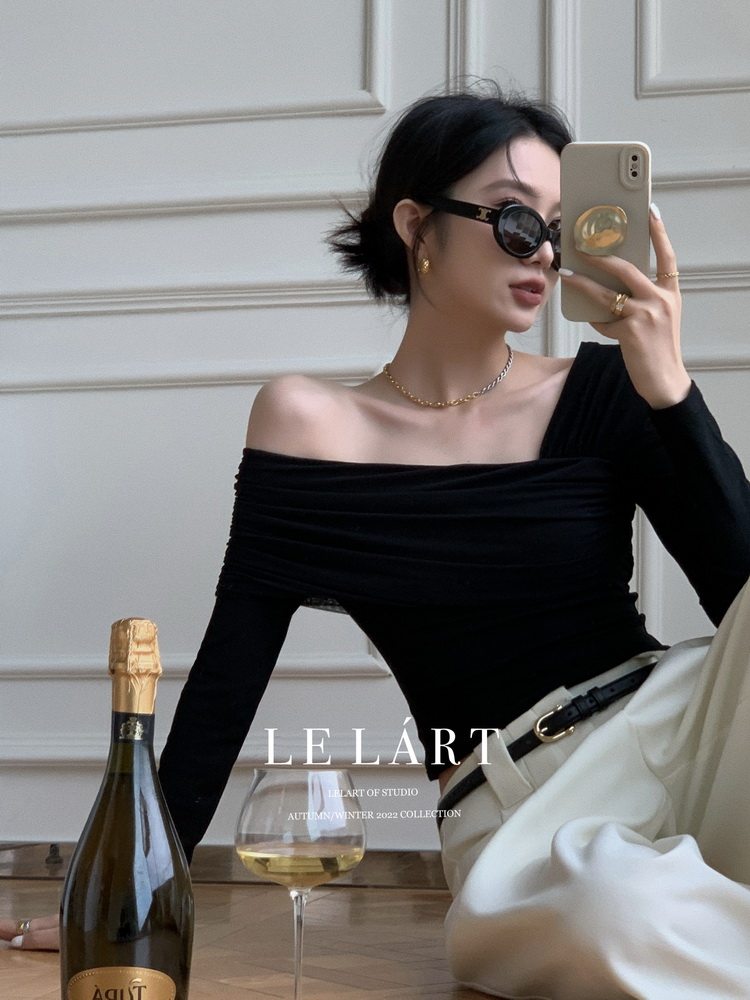 Woman wearing a black off-shoulder top with white pants in a fashion mirror selfie