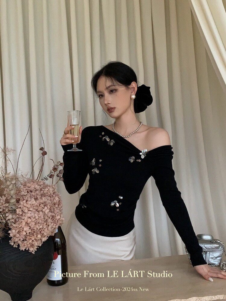 Model wearing a black off-shoulder embellished top with a white skirt