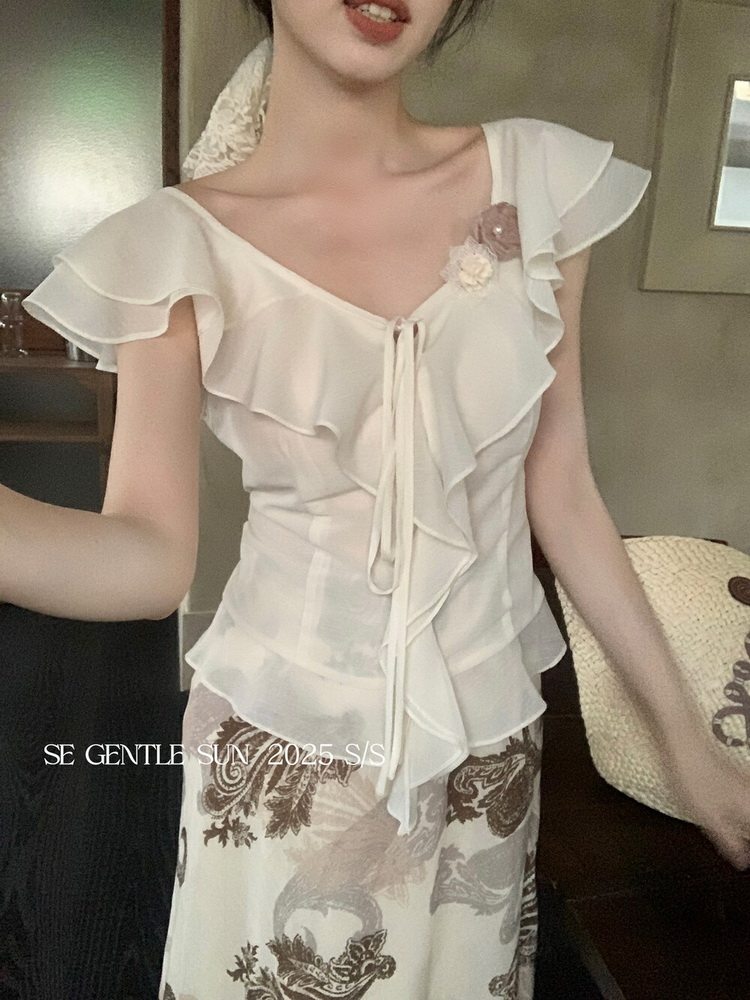 Woman wearing a white ruffled sleeveless blouse with a patterned skirt