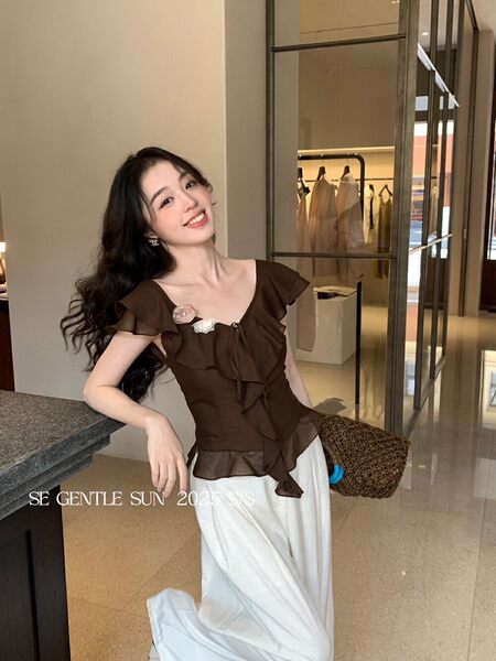 Brown ruffled sleeveless top worn with white skirt pants
