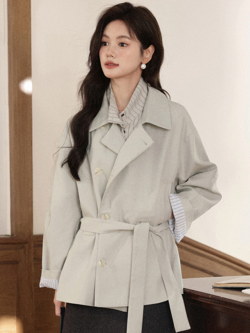 Model wearing a light beige belted trench-style coat