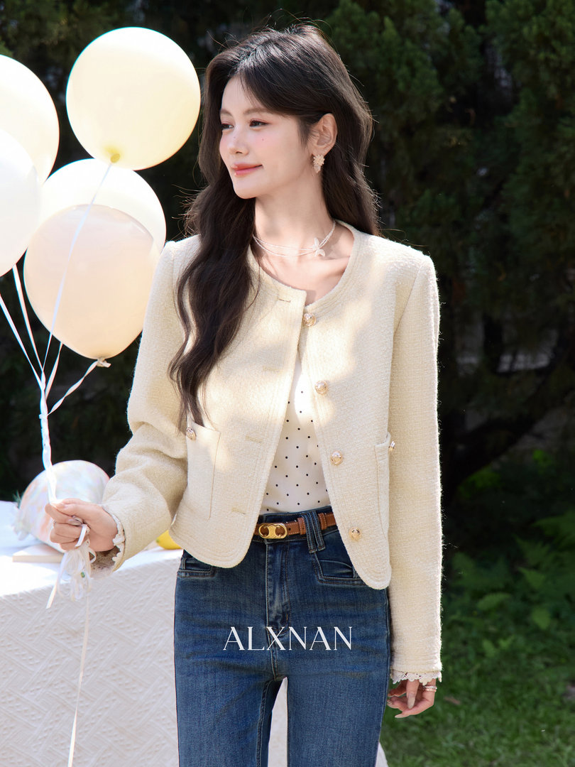 Model wearing a cream cropped jacket over a polka dot top with blue jeans