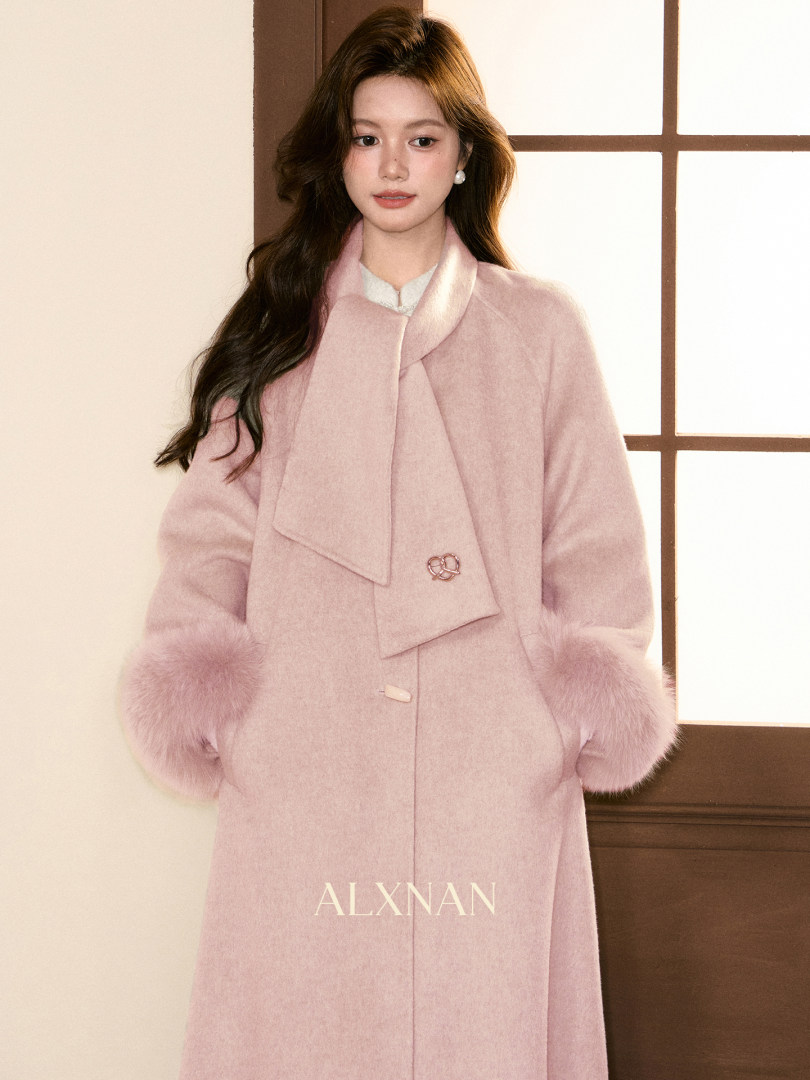 Model wearing a light pink wool coat with fur-trimmed cuffs