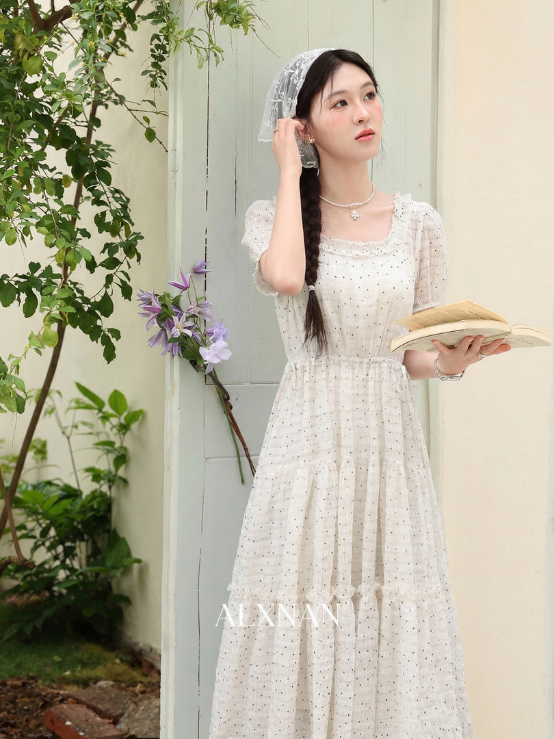 Woman wearing a white lace dress with puff sleeves and tiered skirt