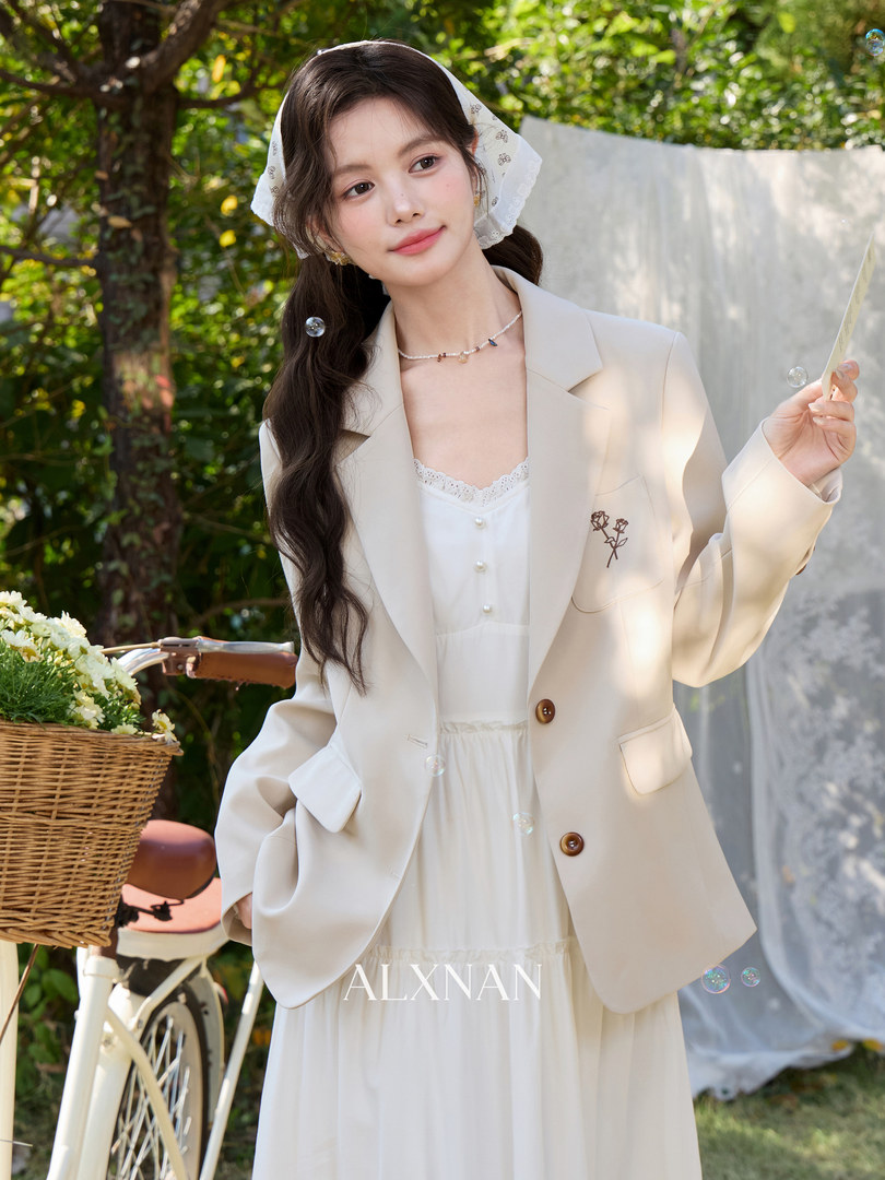 Woman wearing a cream blazer over a white dress outdoors