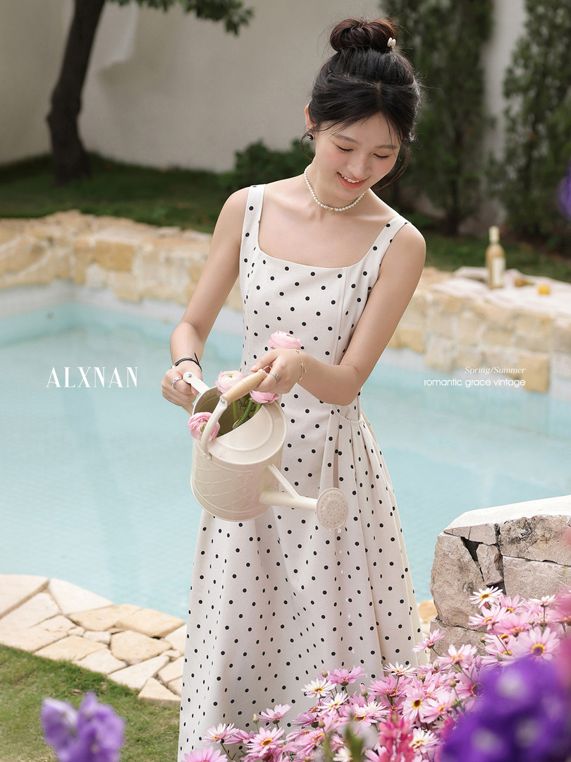 Woman wearing a white polka dot sleeveless dress by a pool