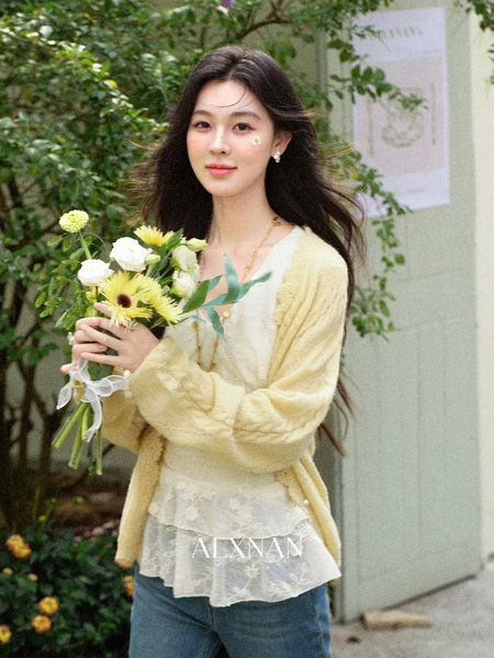 Woman wearing a pale yellow cardigan over a lace top, holding a bouquet of flowers
