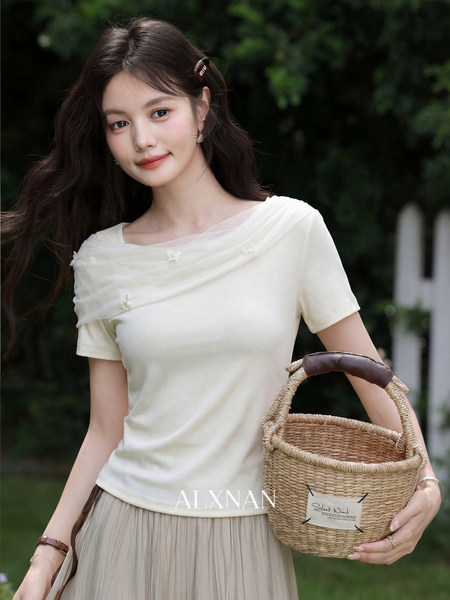 Woman wearing a cream short-sleeve top and pleated skirt while holding a woven basket bag