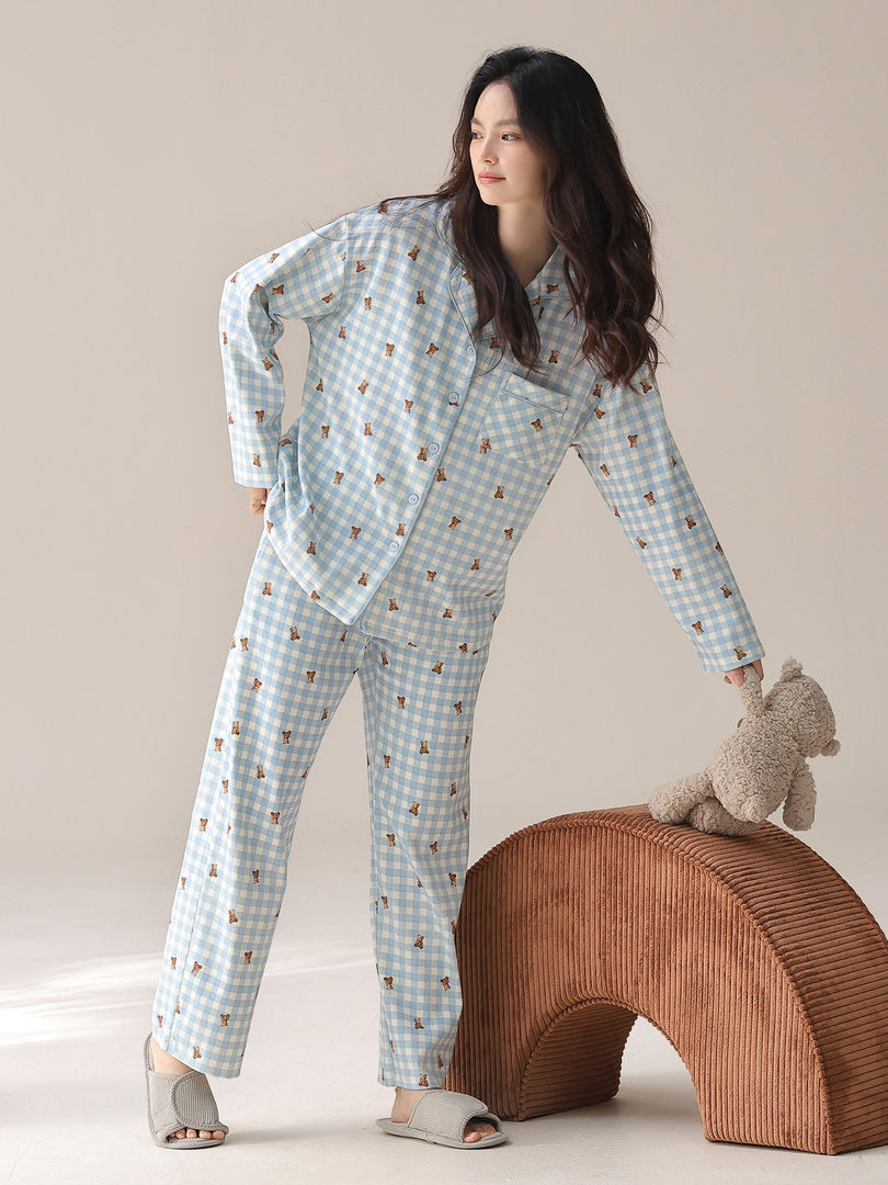 Model wearing light blue patterned pajama set with matching pants and slippers