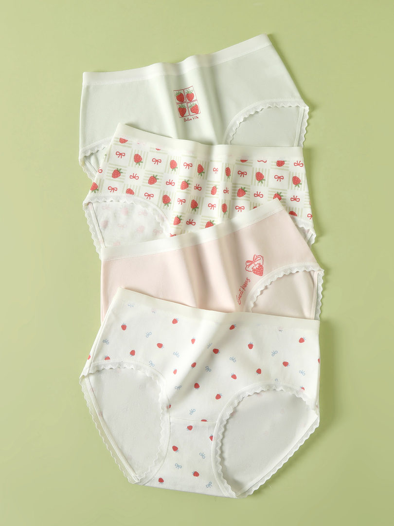 Four pairs of strawberry-patterned women’s underwear laid flat on a green background