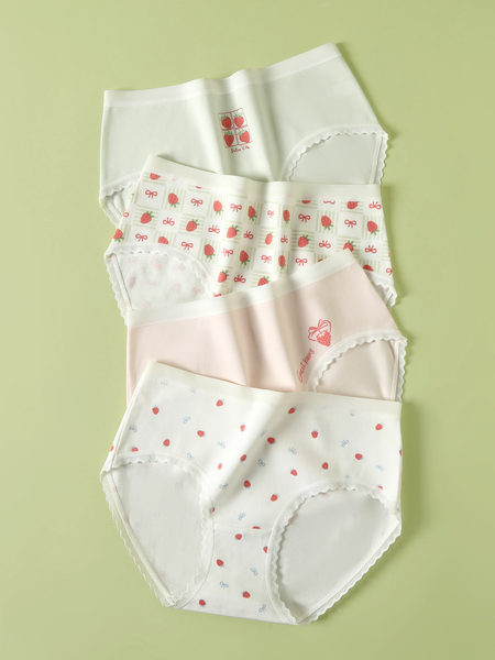 Four pairs of strawberry-patterned women’s underwear laid flat on a green background