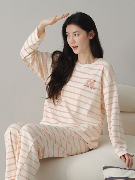 Woman wearing a cream and pink striped pajama set with a "SILLY BEAR" graphic