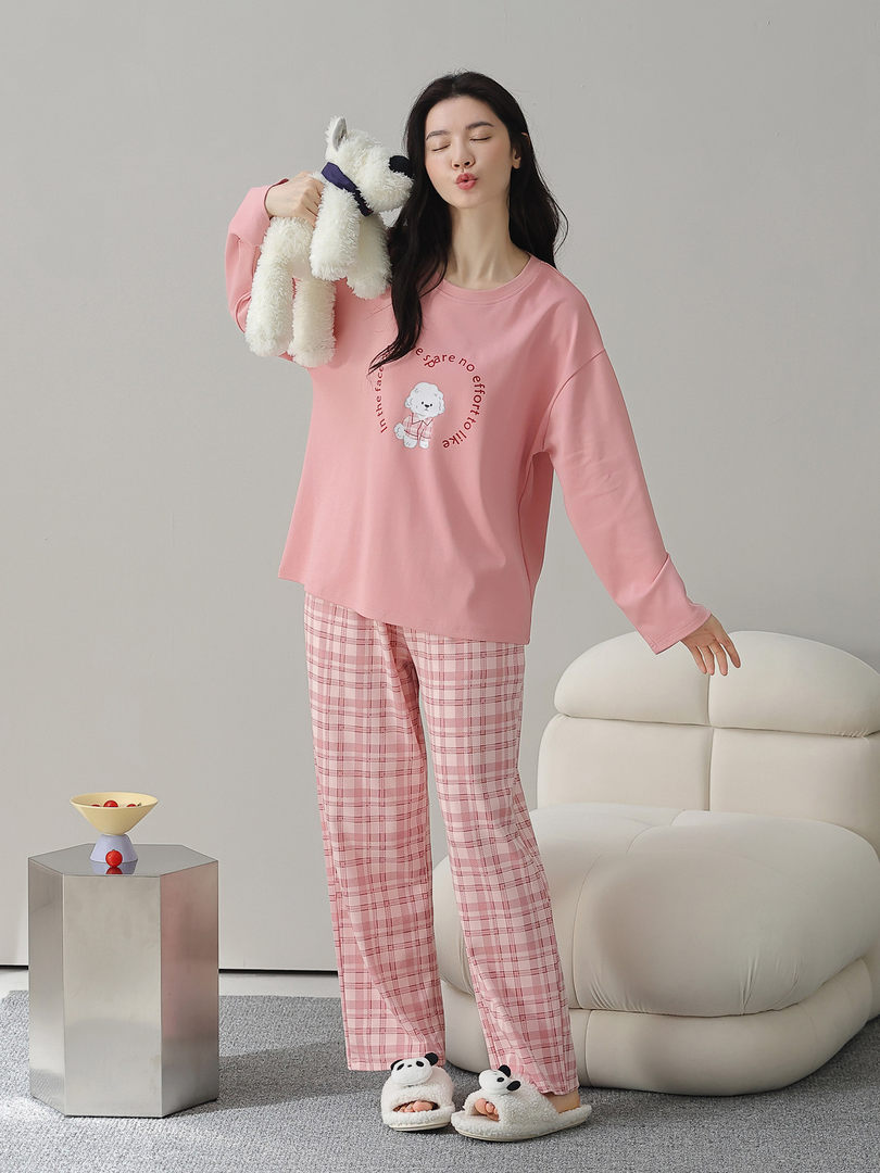 Pink loungewear pajama set worn by a model with plaid pants and fuzzy slippers
