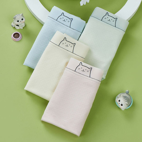 Folded pastel cat-themed underwear or shorts displayed on a green background