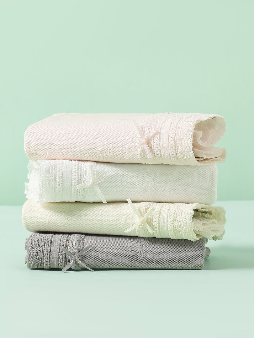Stack of folded lace underwear in white and gray on a mint background