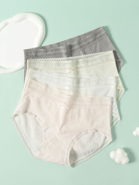 Set of lace-trimmed women’s panties laid flat on a pastel background