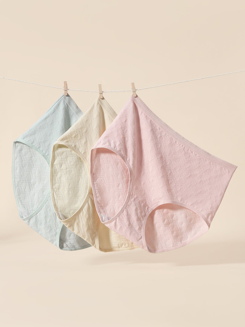 Pastel lace-patterned women's underwear briefs hanging on a line