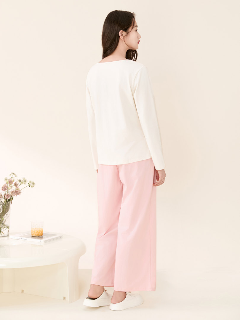 Model wearing a white long-sleeve top with pink wide-leg pants