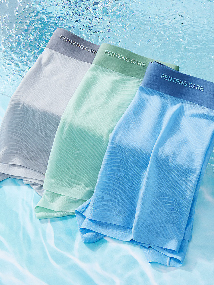 Three pairs of men’s boxer briefs in gray, mint, and blue laid flat
