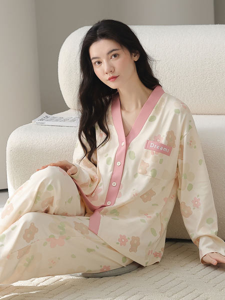 Woman wearing a pastel printed pajama set with pink trim and "Dreams" patch
