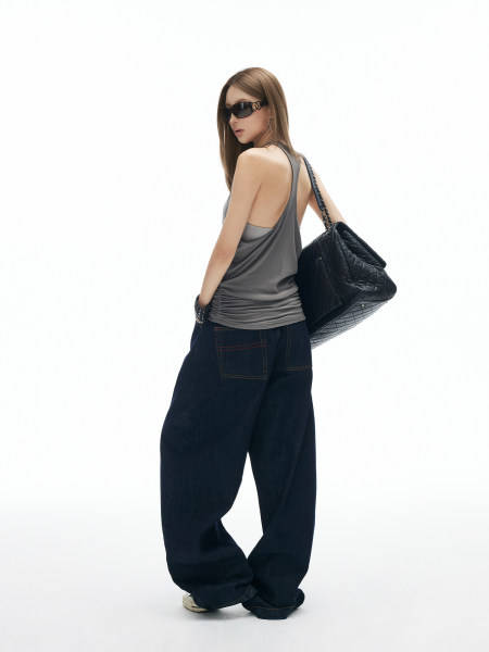 Model wearing a gray tank top, wide-leg dark jeans, and a black quilted shoulder bag