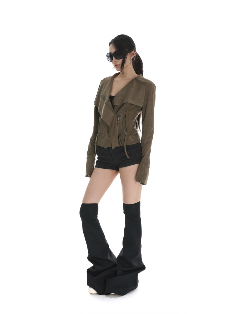 Model wearing an olive cropped jacket with black shorts and tall black boots