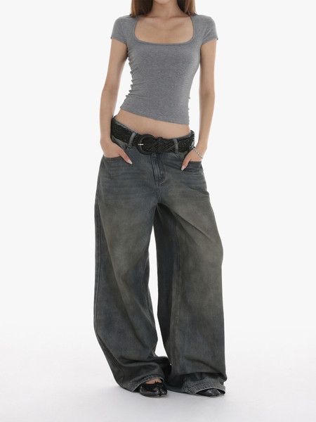 Woman wearing a gray fitted short-sleeve top with wide-leg jeans and a belt