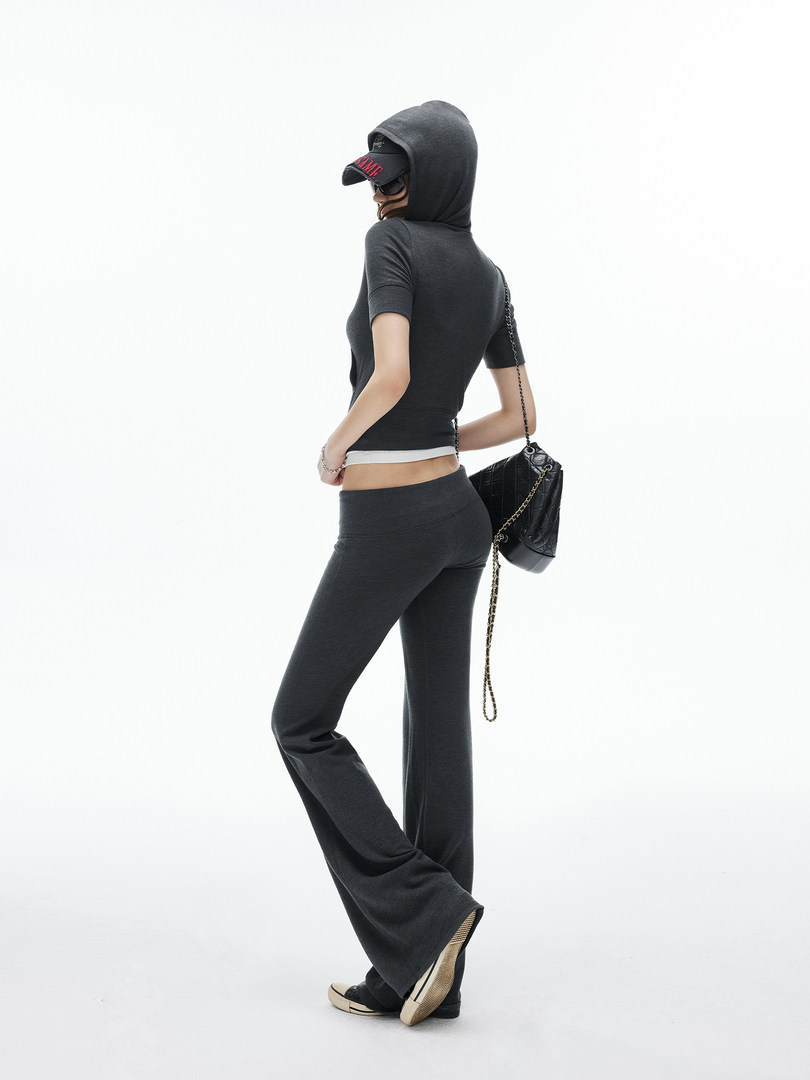 Model wearing a dark fitted hooded top and flared pants with a black chain-strap bag