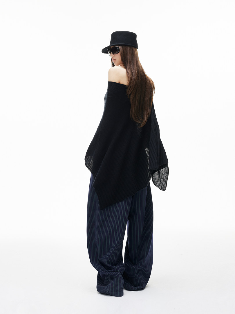 Model wearing a black off-shoulder top with wide pinstripe pants, hat, and sunglasses