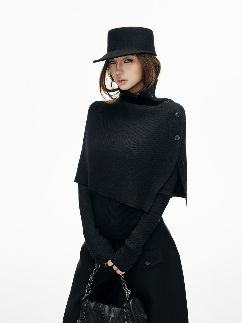 Model wearing a black knit poncho-style top with matching hat and handbag