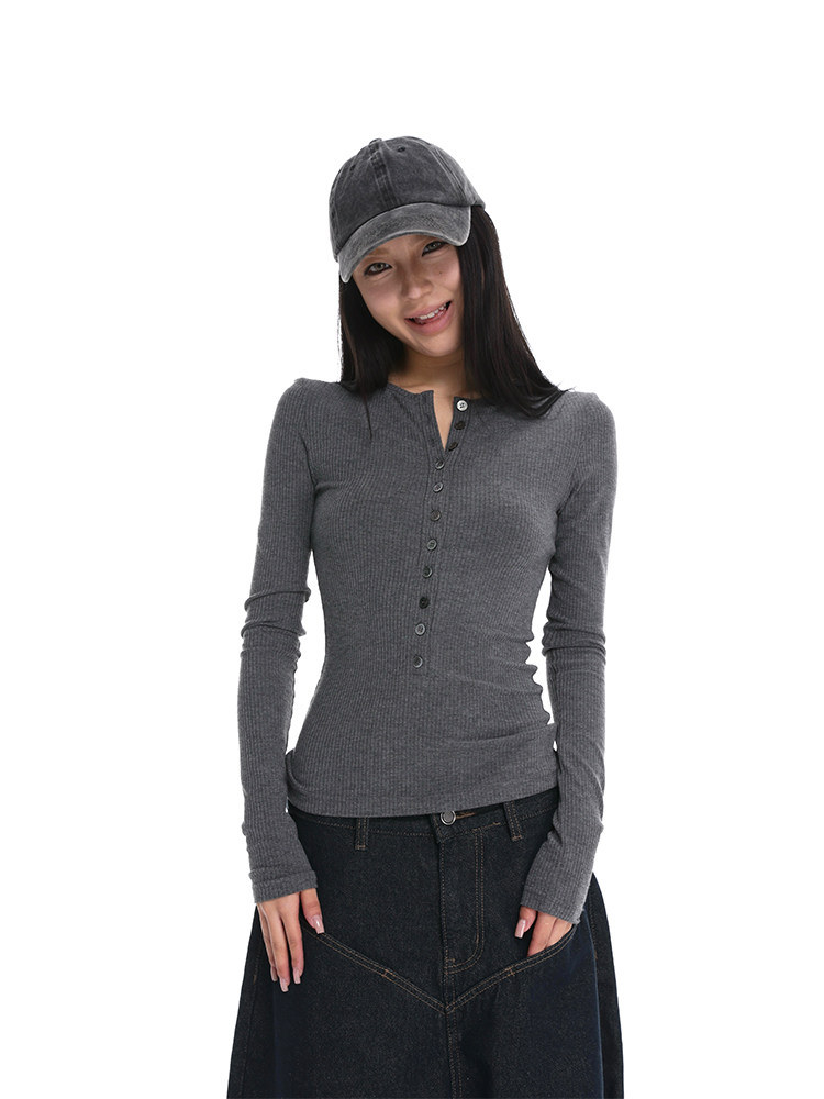 Woman wearing a gray long-sleeve ribbed henley top with a black cap