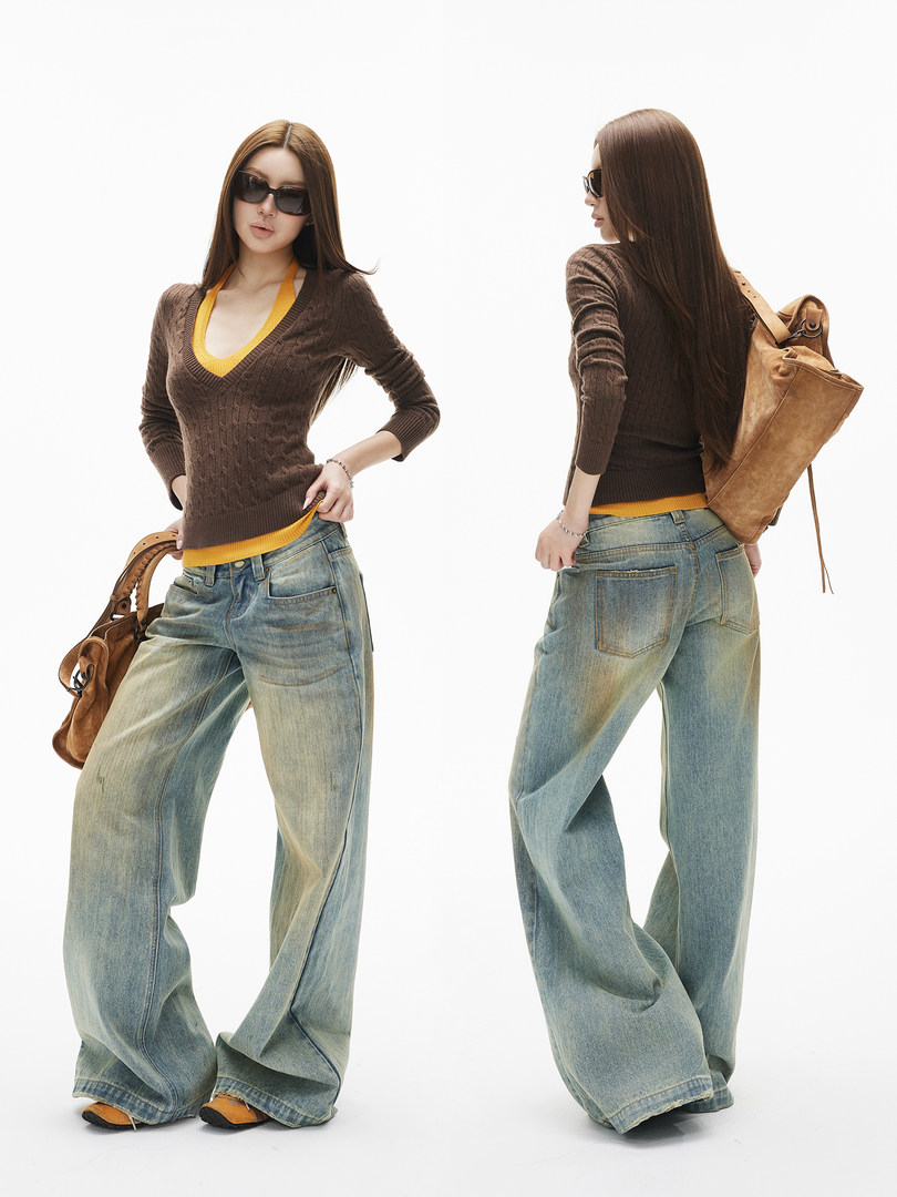 Model wearing wide-leg faded jeans with a brown knit sweater and tan shoulder bag