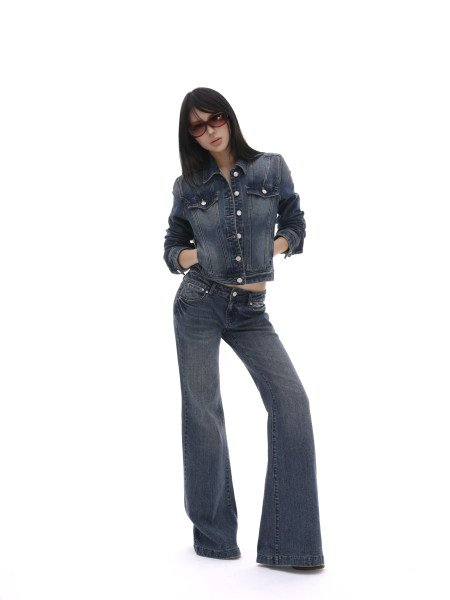 Model wearing a dark denim jacket and flared jeans on a white background