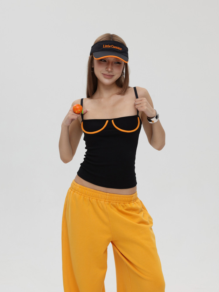 Model wearing a black spaghetti-strap top, yellow pants, and a black visor cap