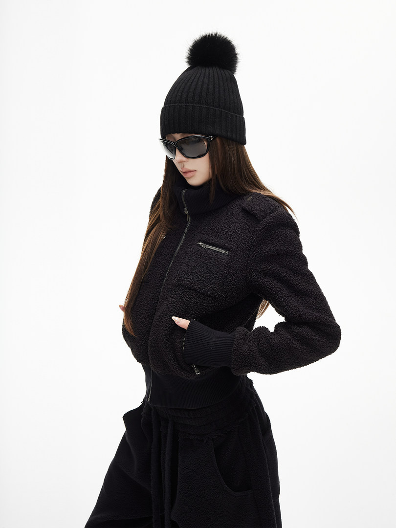 Model wearing a black winter beanie and textured black jacket on a white background