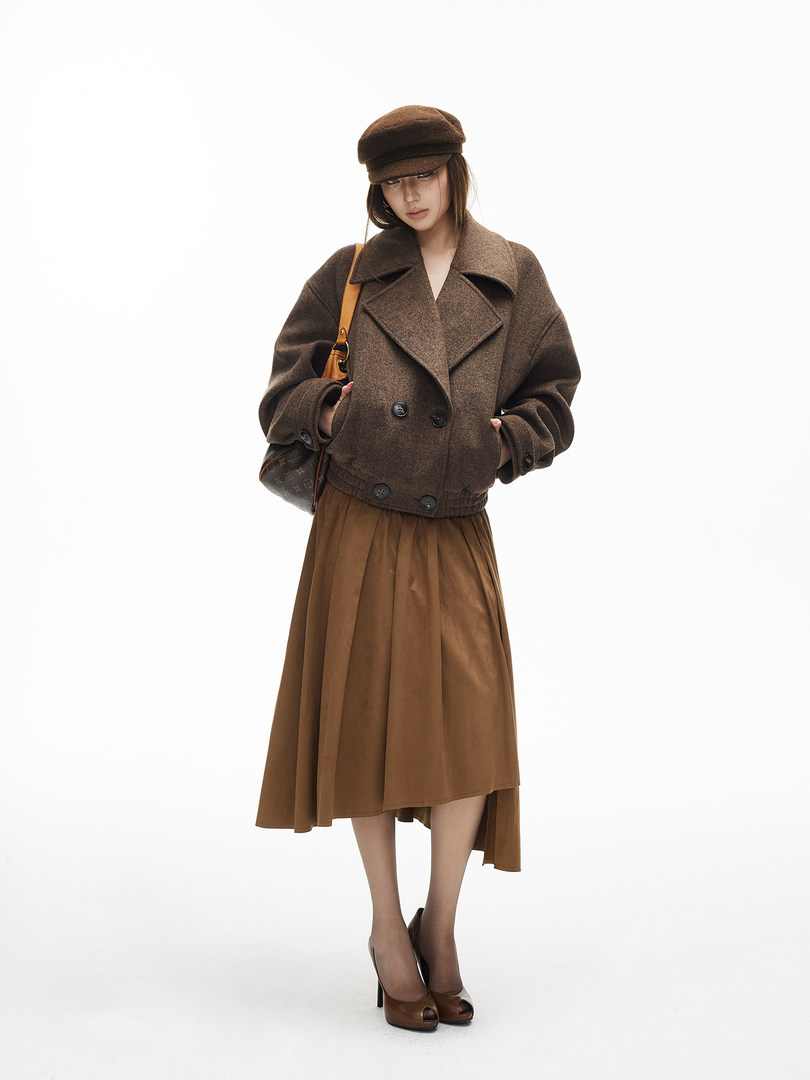 Model wearing a brown wool coat, matching skirt, and cap with heeled shoes