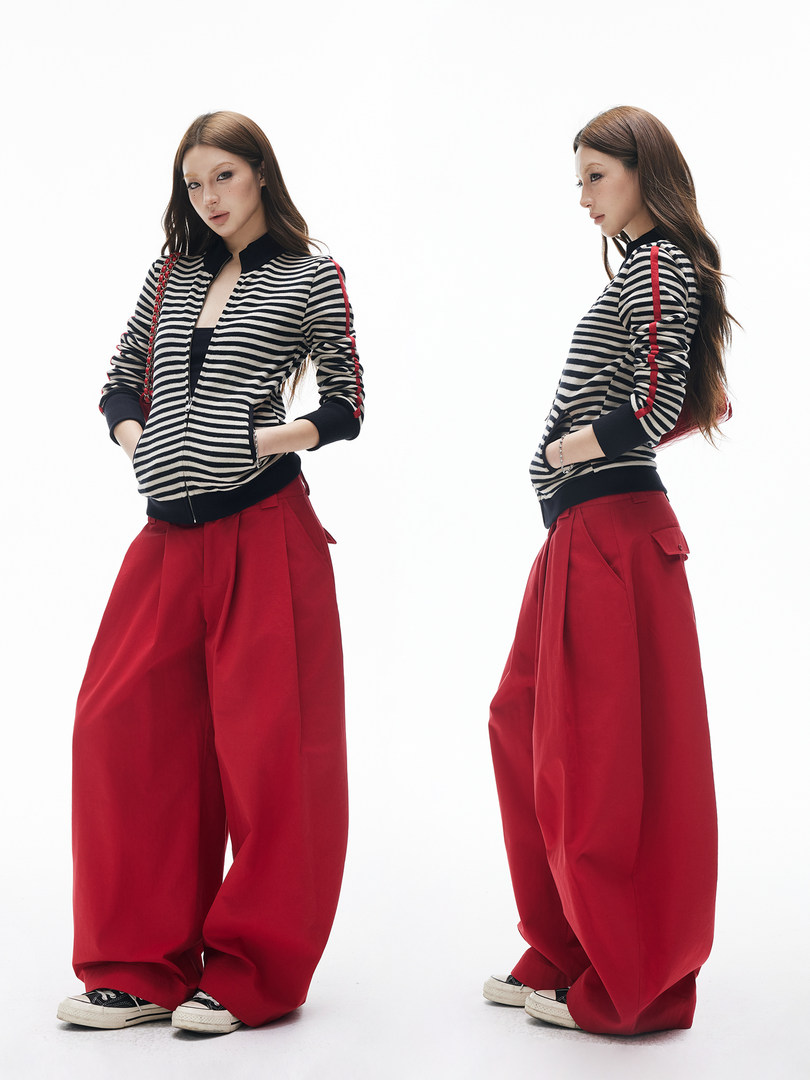 Model wearing a black-and-white striped zip jacket with red wide-leg pants on a white background